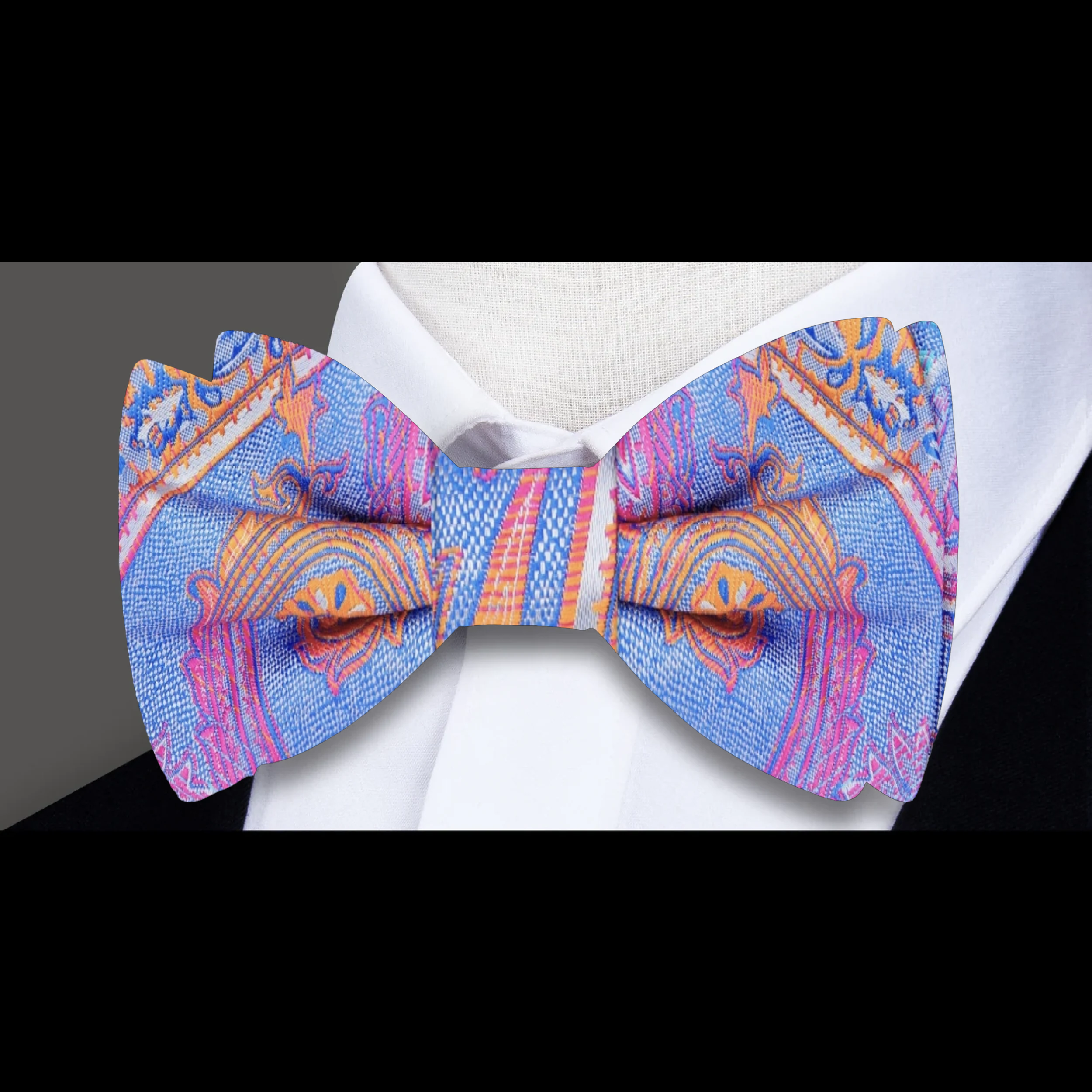 Man wearing a vibrant paisley bow tie paired with a light grey suit at a garden party.