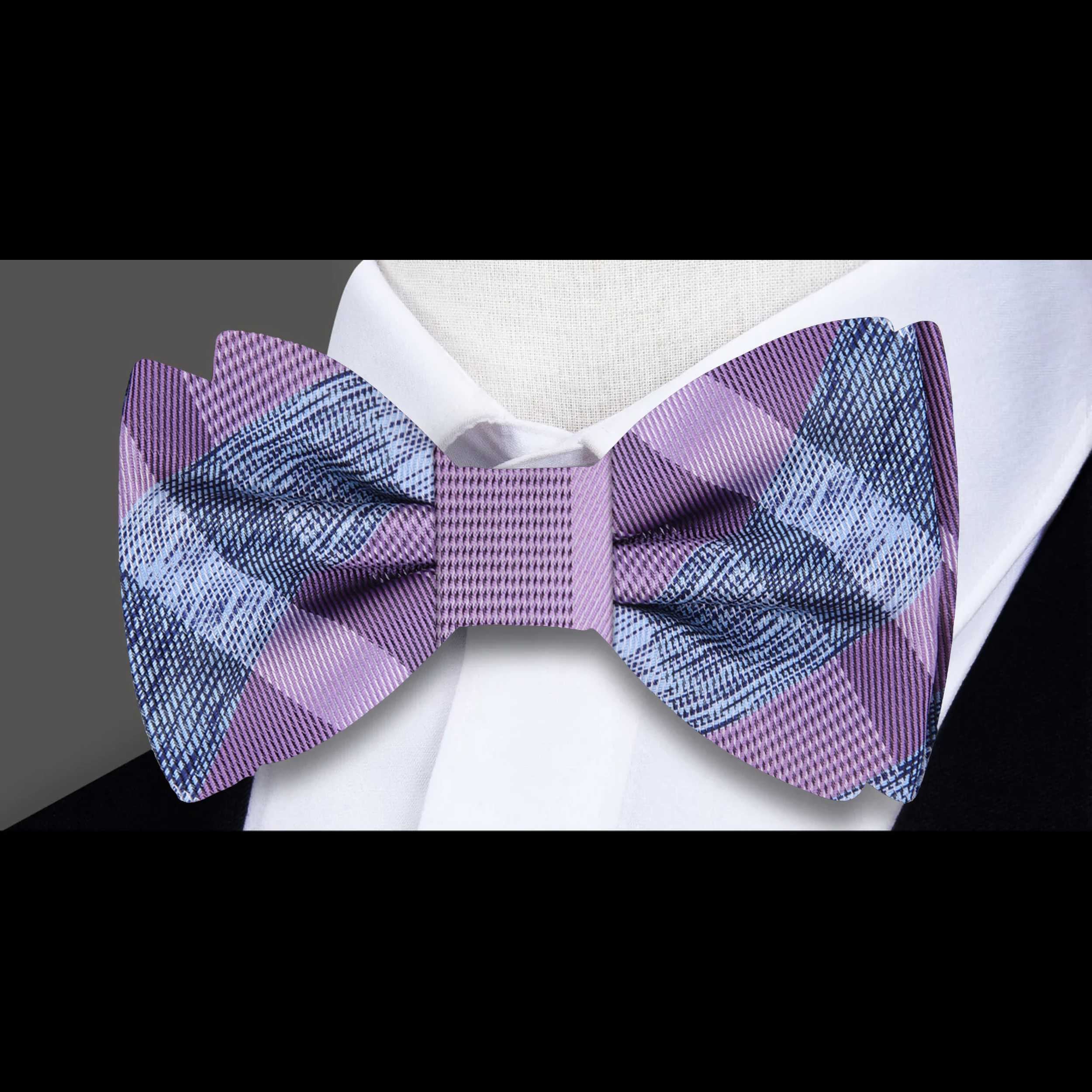 Model wearing plaid bow tie and matching pocket square with suit