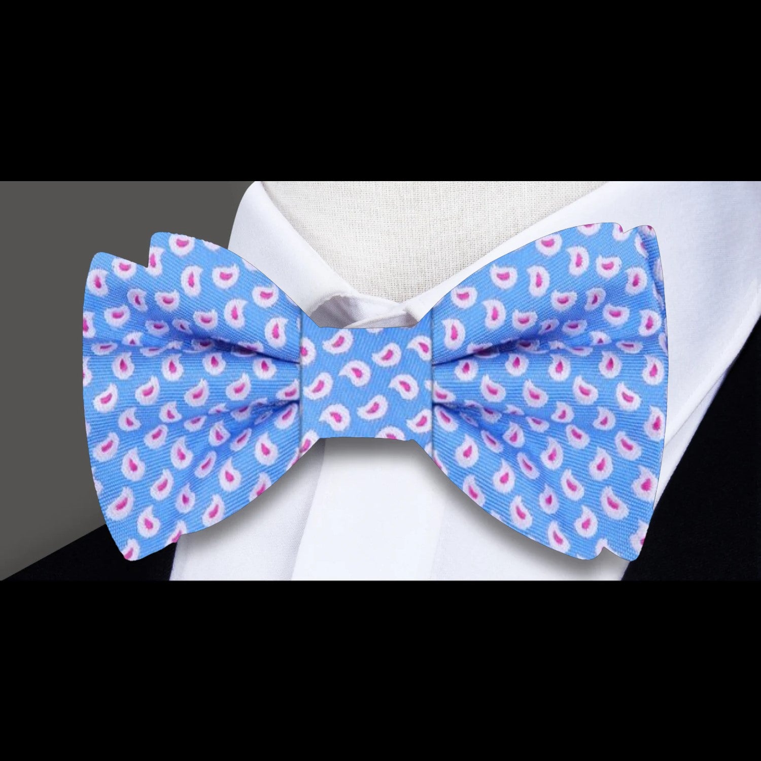 Light blue paisley silk bow tie paired with a navy suit, ideal for formal events and weddings.