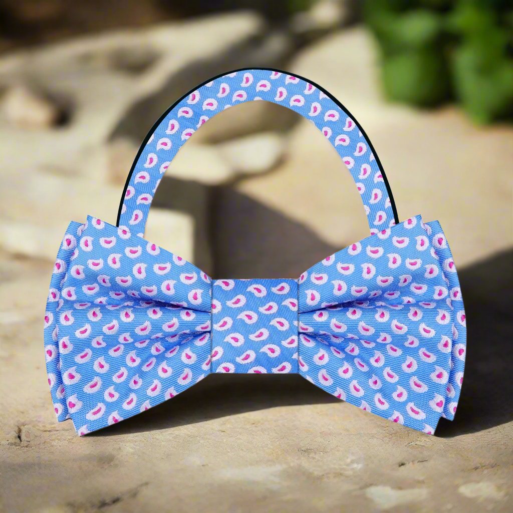 Elegant light blue paisley silk bow tie displayed against a crisp white shirt, showcasing its intricate design.