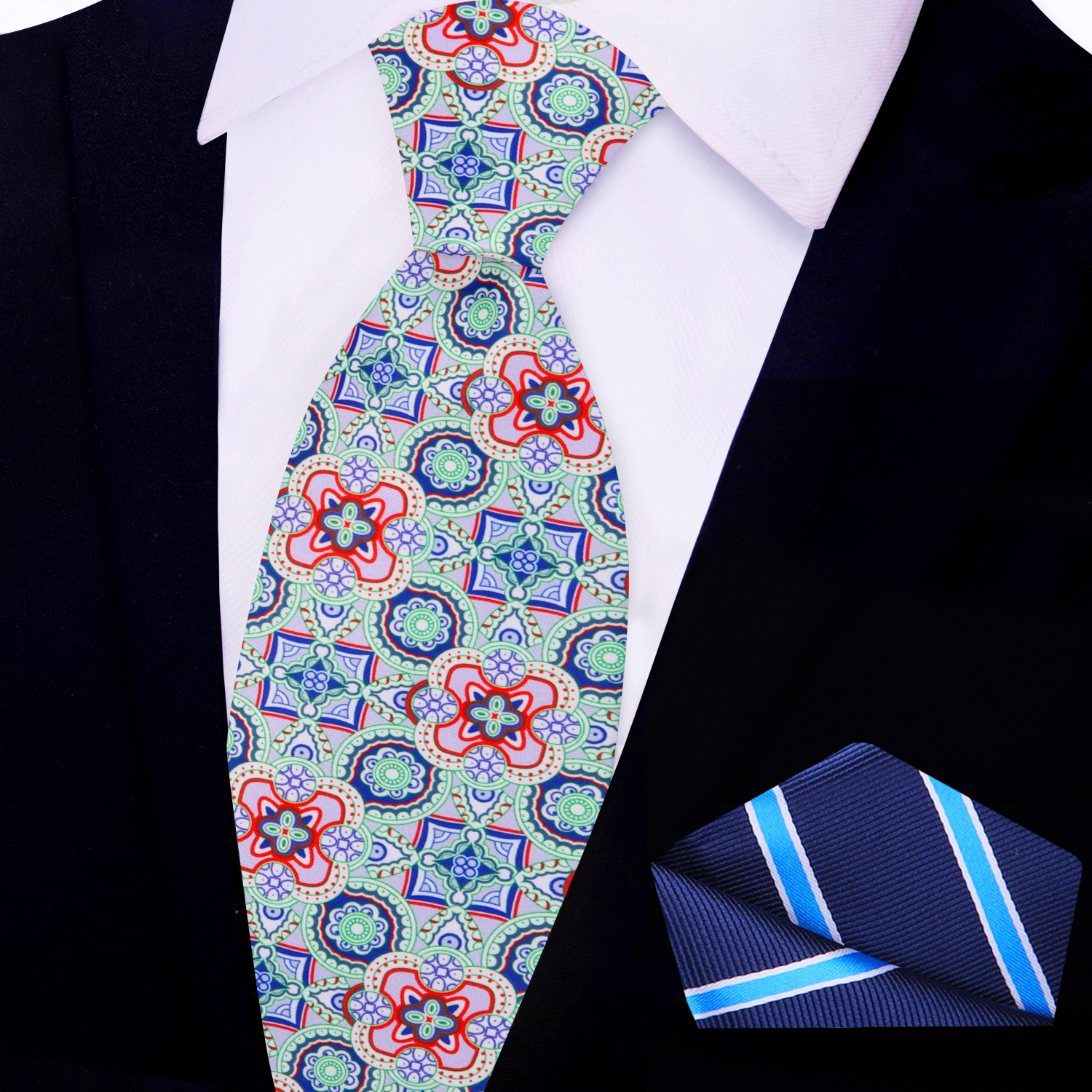 Flat lay of vibrant mosaic necktie paired with a light grey suit and a white dress shirt.