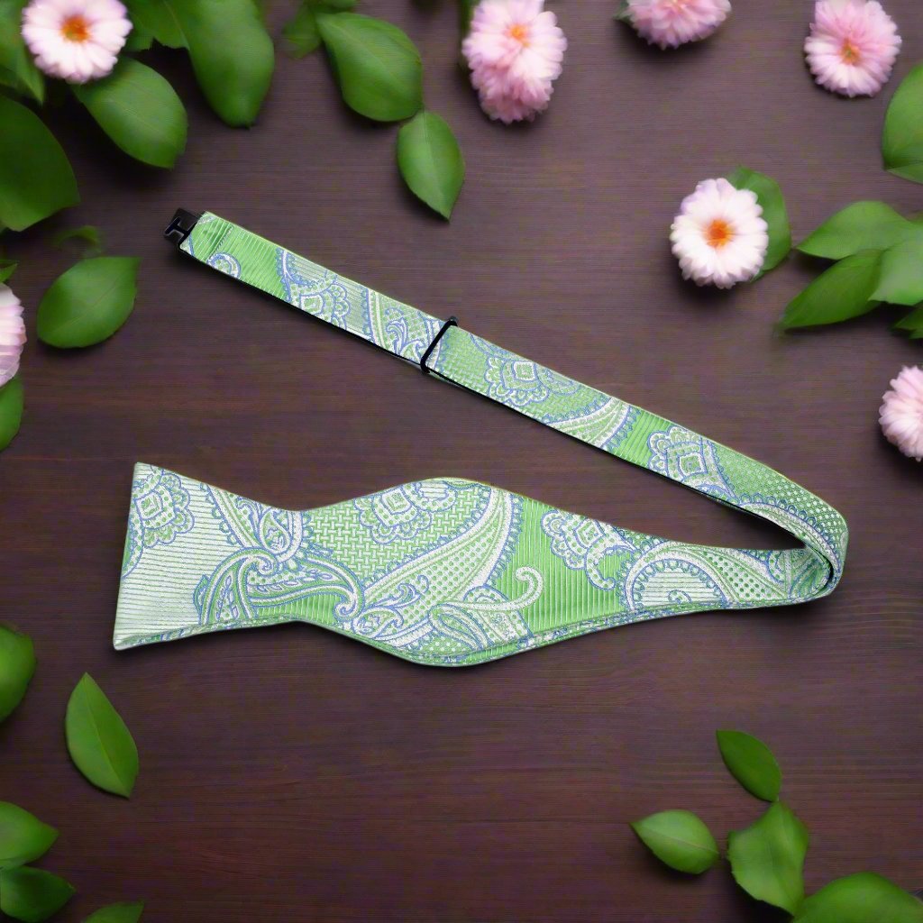 Model wearing a vibrant green paisley bow tie with a charcoal gray suit at a formal event.