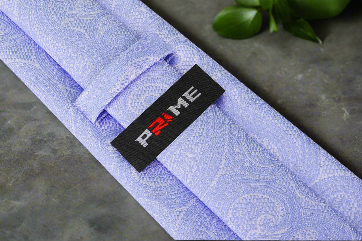 Styled shot of the grey paisley necktie paired with a crisp white shirt and navy blazer, ideal for office wear.