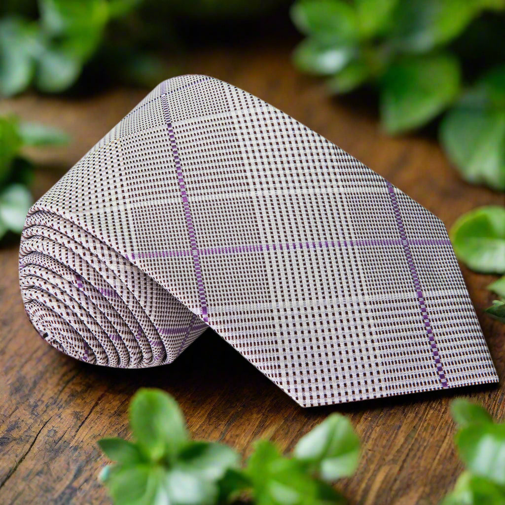 Close-up of grey and purple silk plaid necktie folded neatly with pocket square