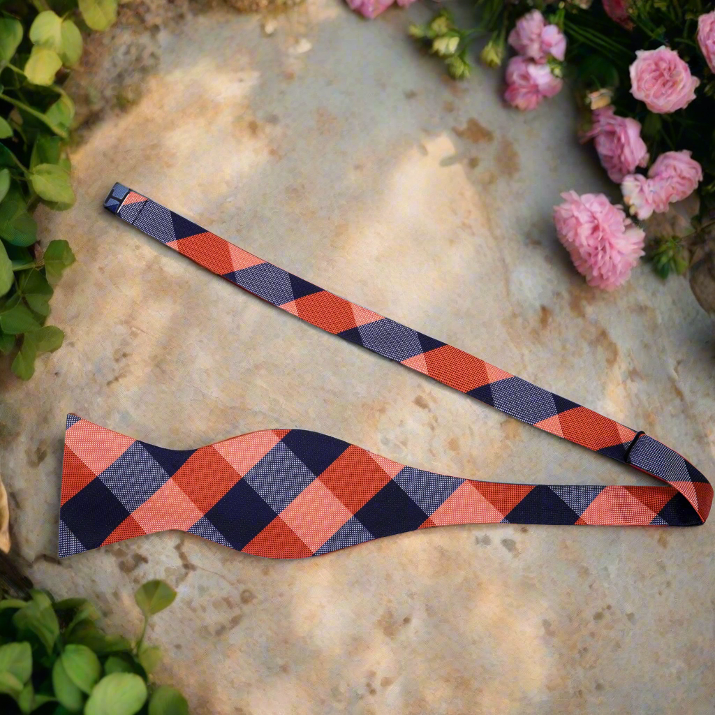 Man adjusting a vibrant plaid self-tie bow tie with a classic suit for a formal event