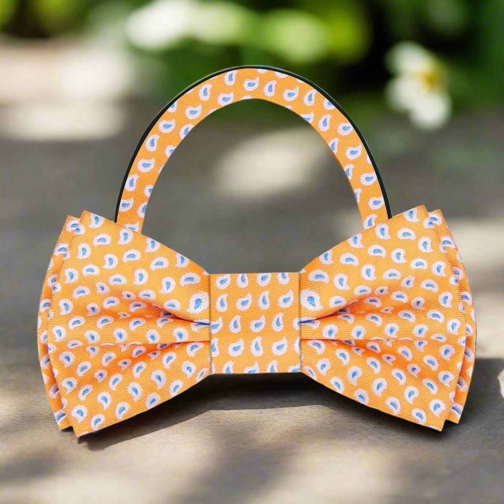 Elegant light blue paisley silk bow tie displayed against a crisp white shirt, showcasing its intricate design.