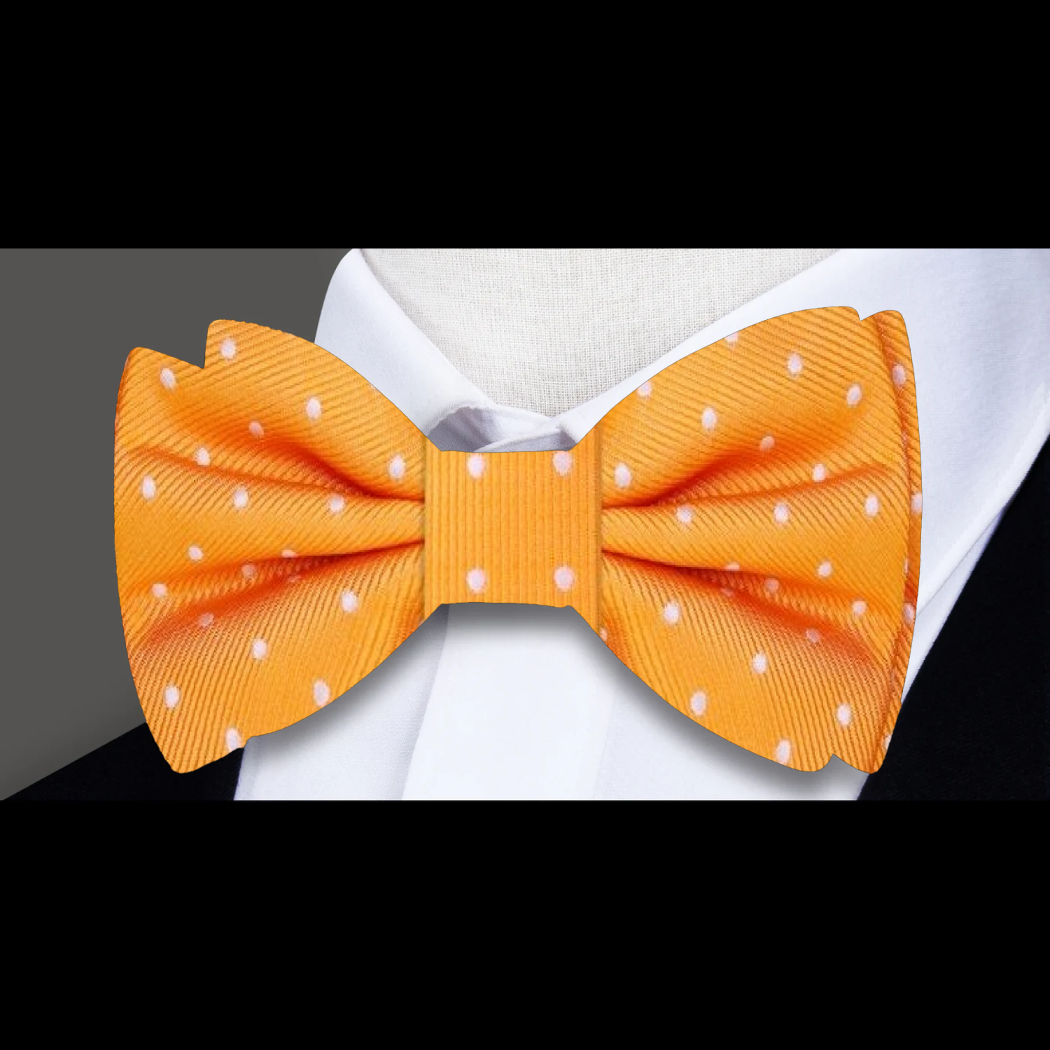 Close-up of navy silk polka dot bow tie with matching pocket square, styled on a white dress shirt