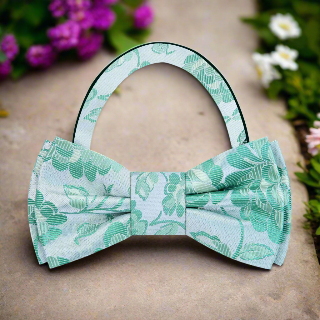Model wearing the pink floral silk bow tie at a garden party, paired with a light blue shirt for a stylish look.