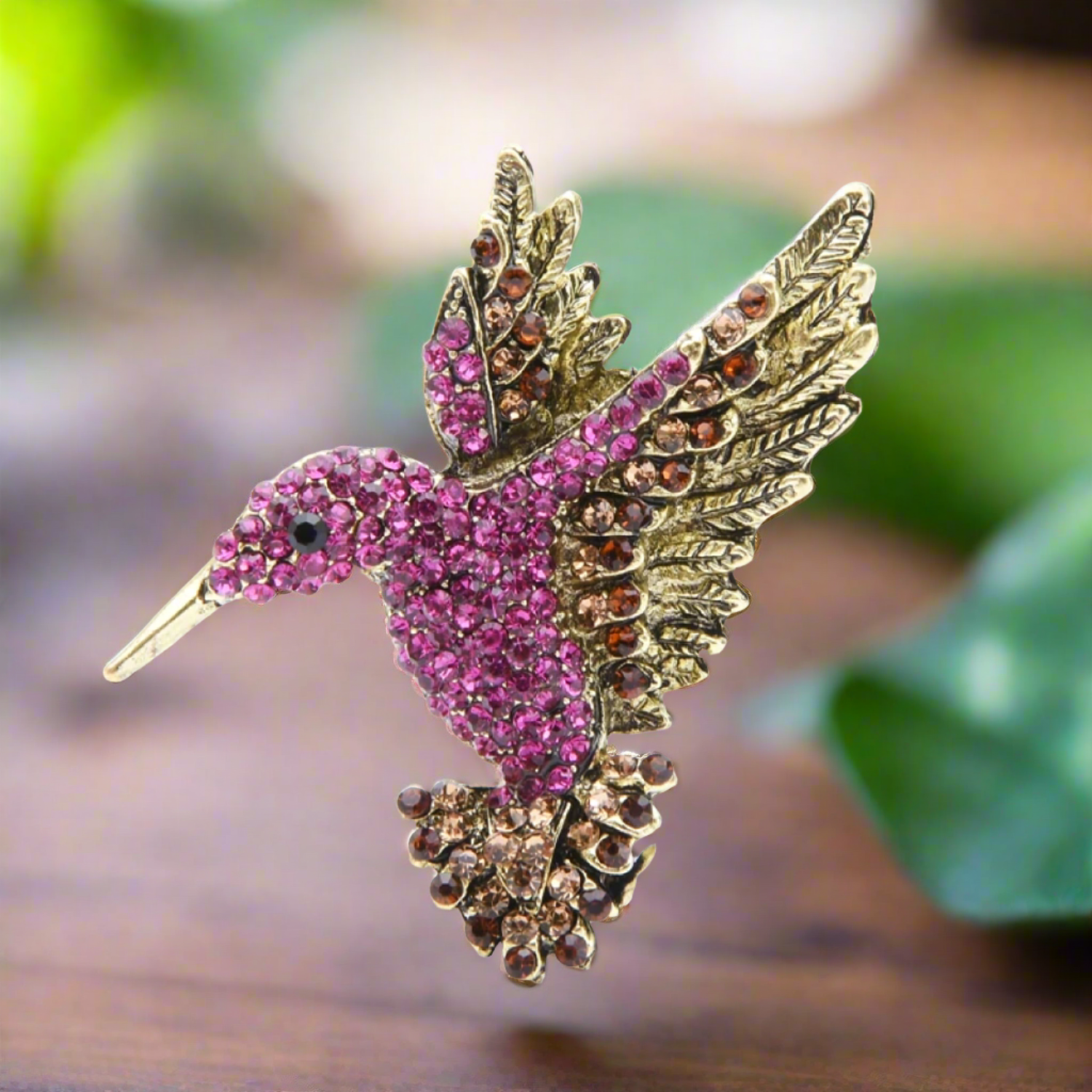 Side angle of the hummingbird lapel pin resting on a colorful scarf, illustrating its versatility as a fashion accessory.