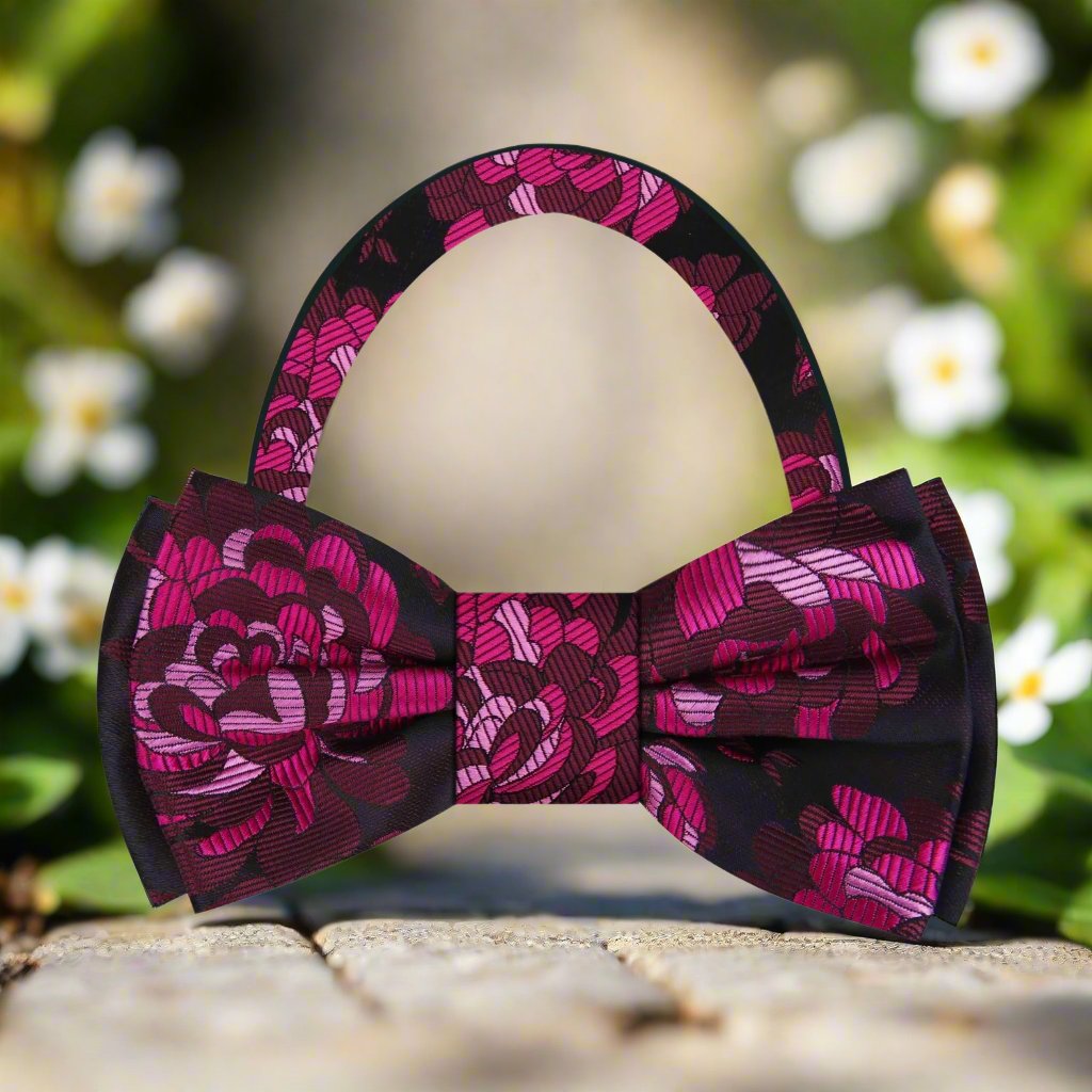 Model wearing the pink floral silk bow tie at a garden party, paired with a light blue shirt for a stylish look.