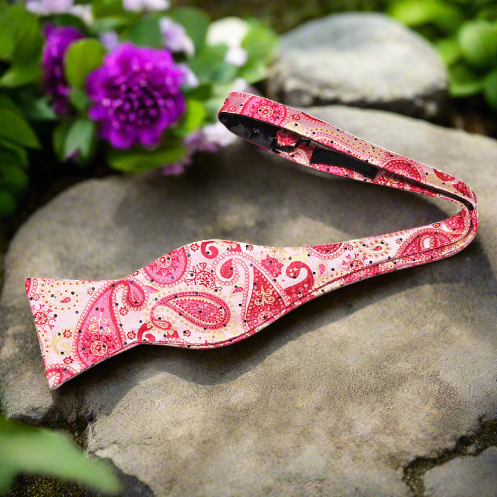 Close-up of vibrant paisley silk self-tie bow tie against a white background.