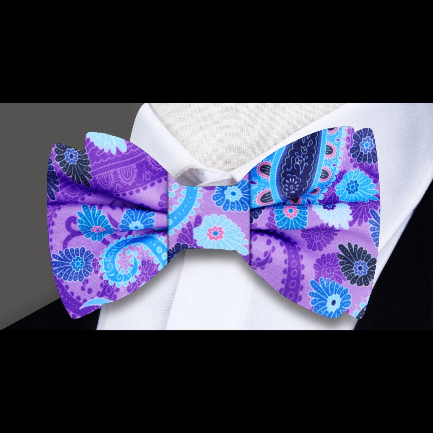 Model wearing the vibrant paisley bow tie paired with a classic white dress shirt, showcasing its elegance.