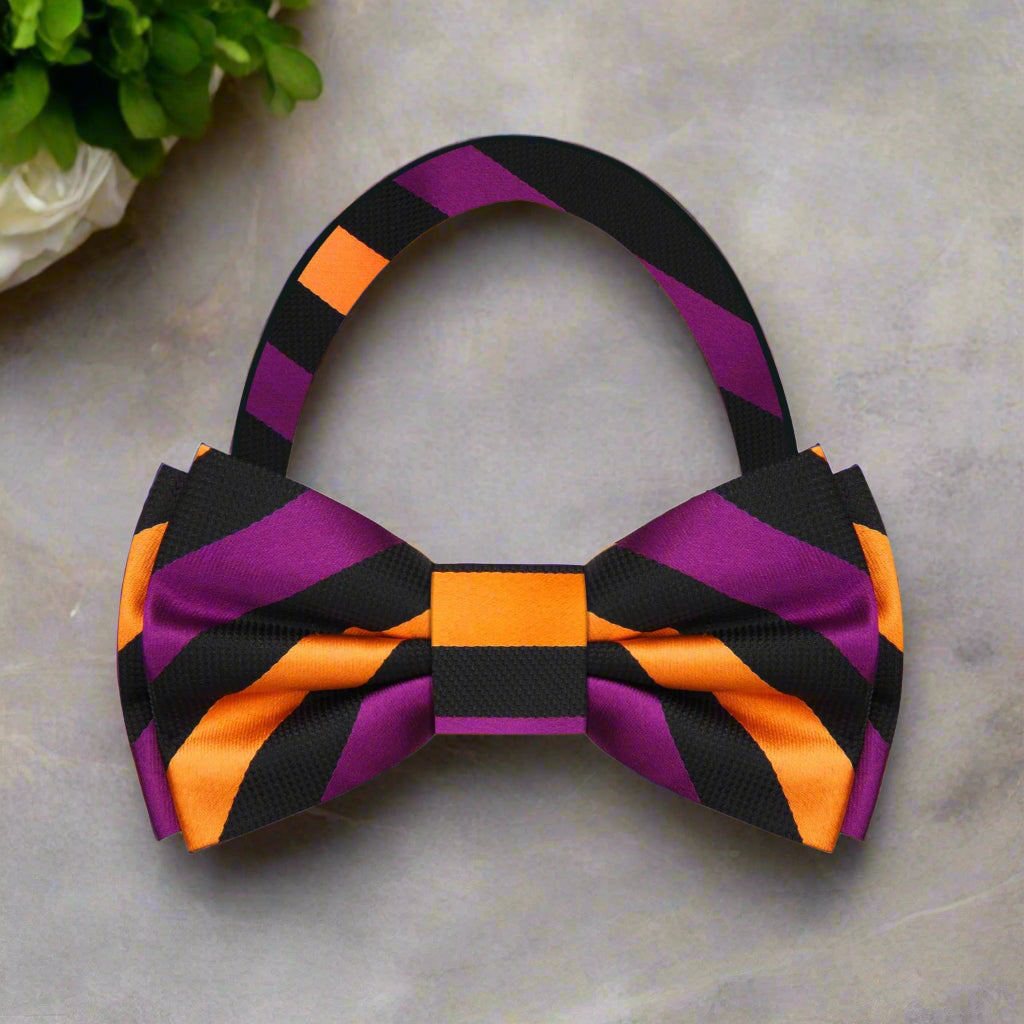 Close-up of a purple and gold stripe bow tie on a mannequin, showcasing detailed silk fabric and vibrant colors.