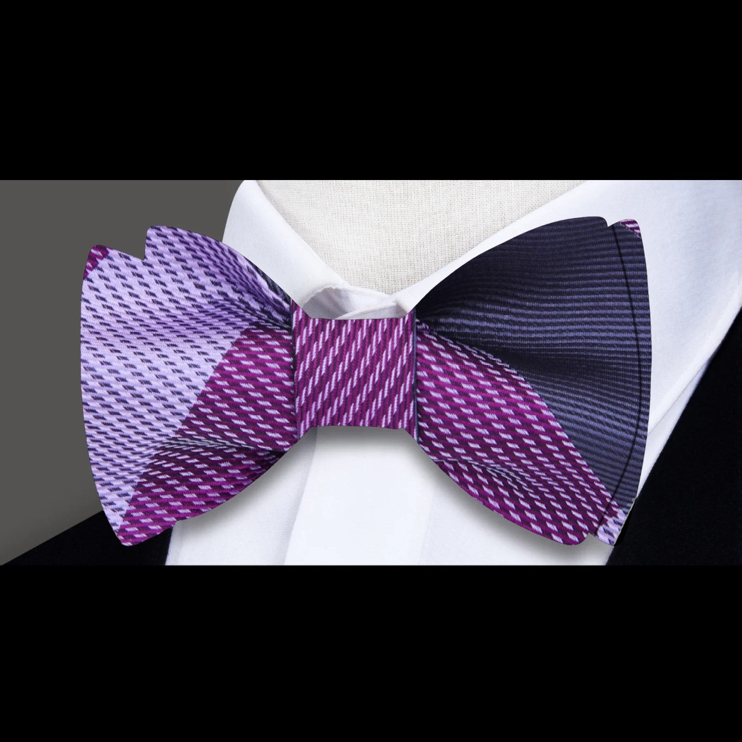 Man wearing a pre-tied plaid bow tie with a navy suit at a formal event