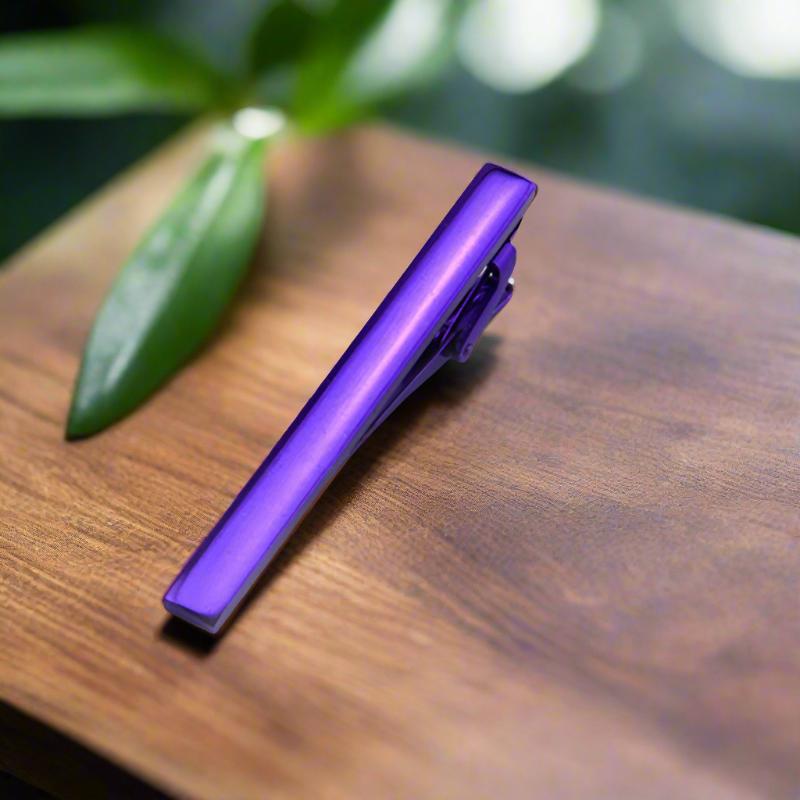 Array of metallic tie clips in seven colors arranged on matte surface