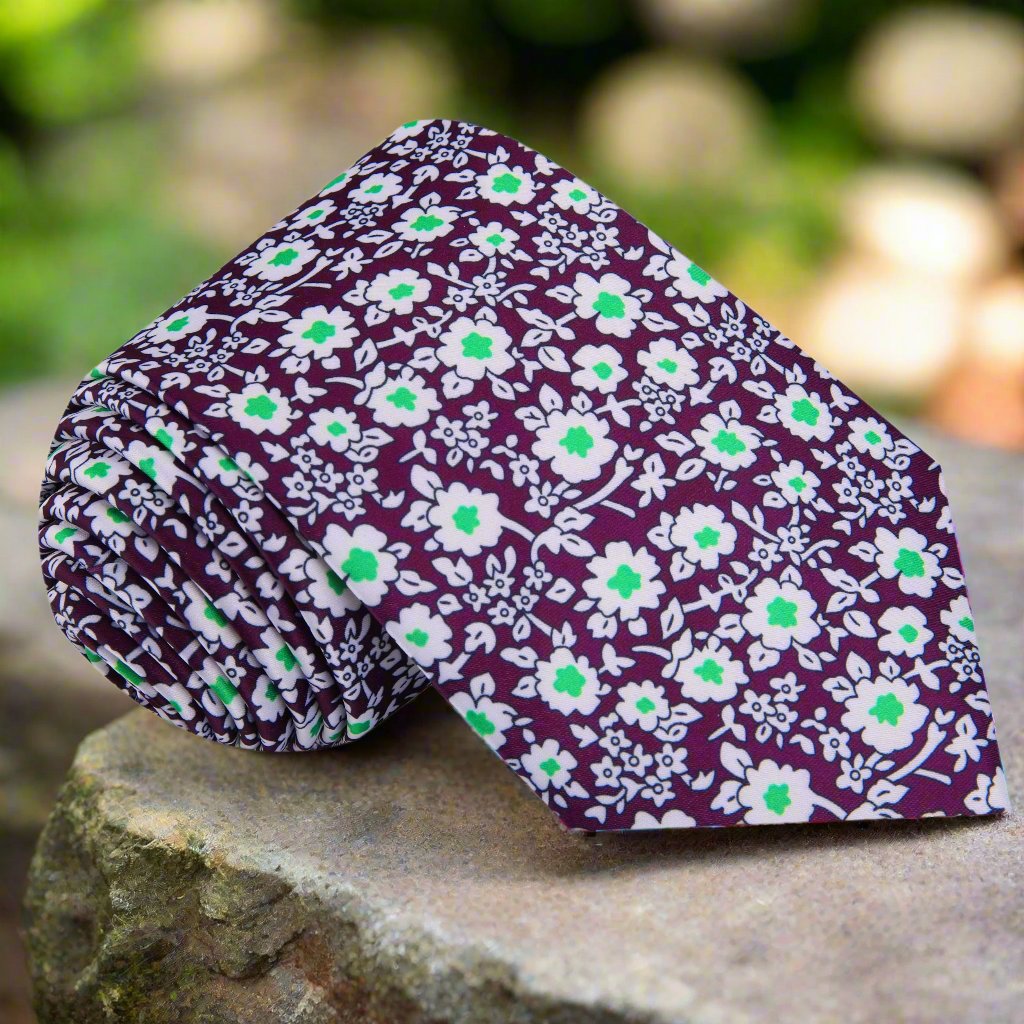 Close-up of plum silk tie with white and green floral pattern, ideal for weddings