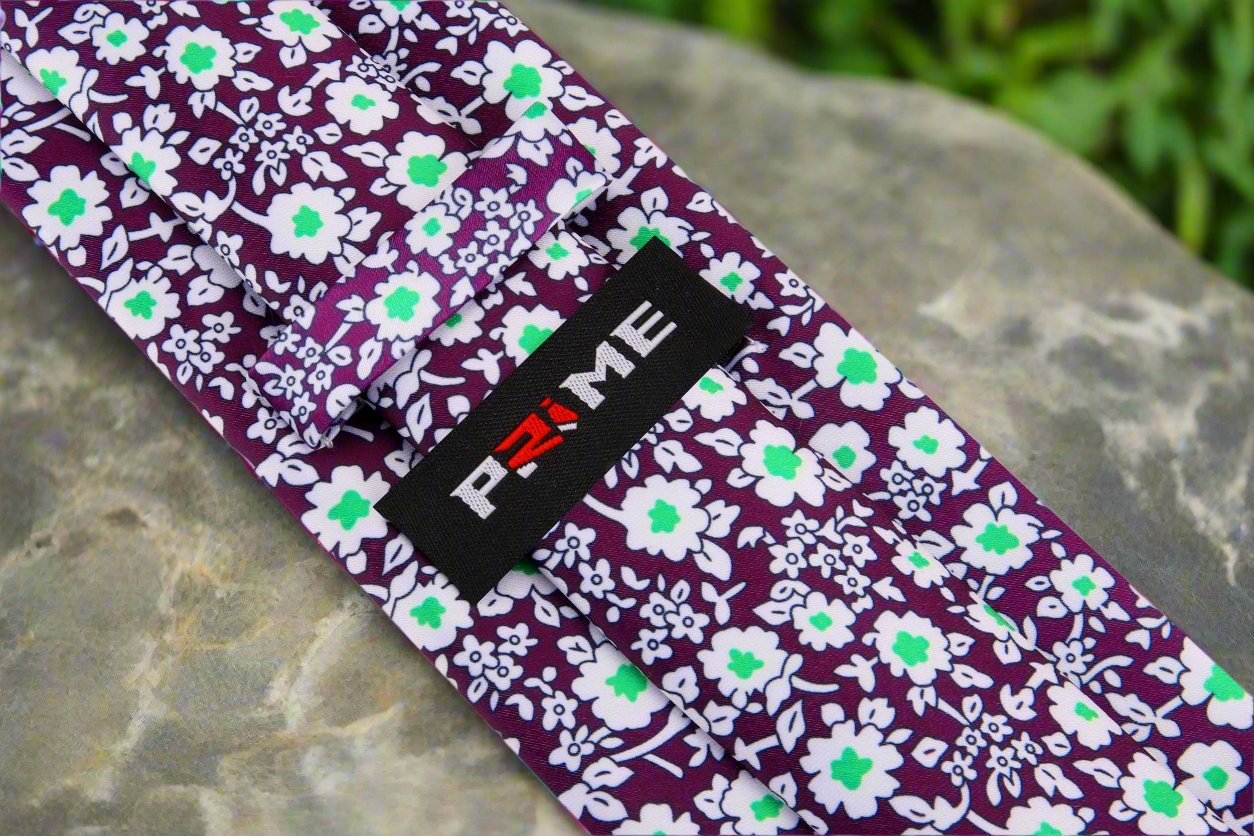 Flat lay of silk necktie and matching pocket square in plum floral design
