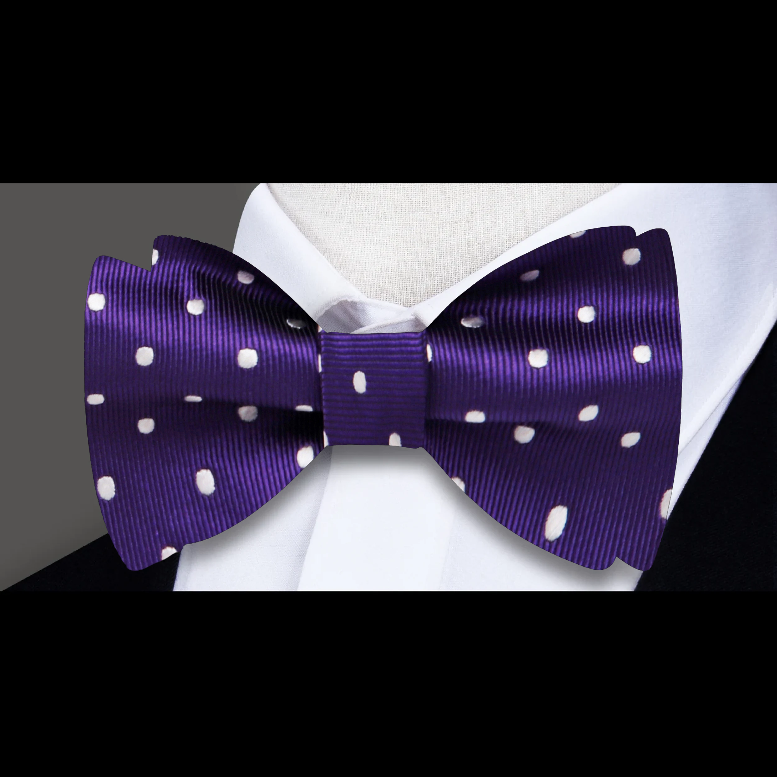Close-up of purple polka dot bow tie with white dots, suitable for formal wear