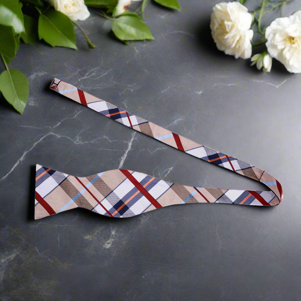 Brown, red, and blue plaid bow tie set displayed on a crisp white shirt.