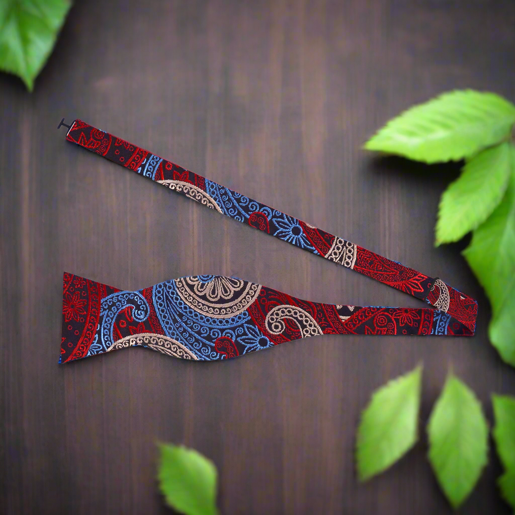 Man adjusting a self-tie paisley bow tie with vibrant pattern