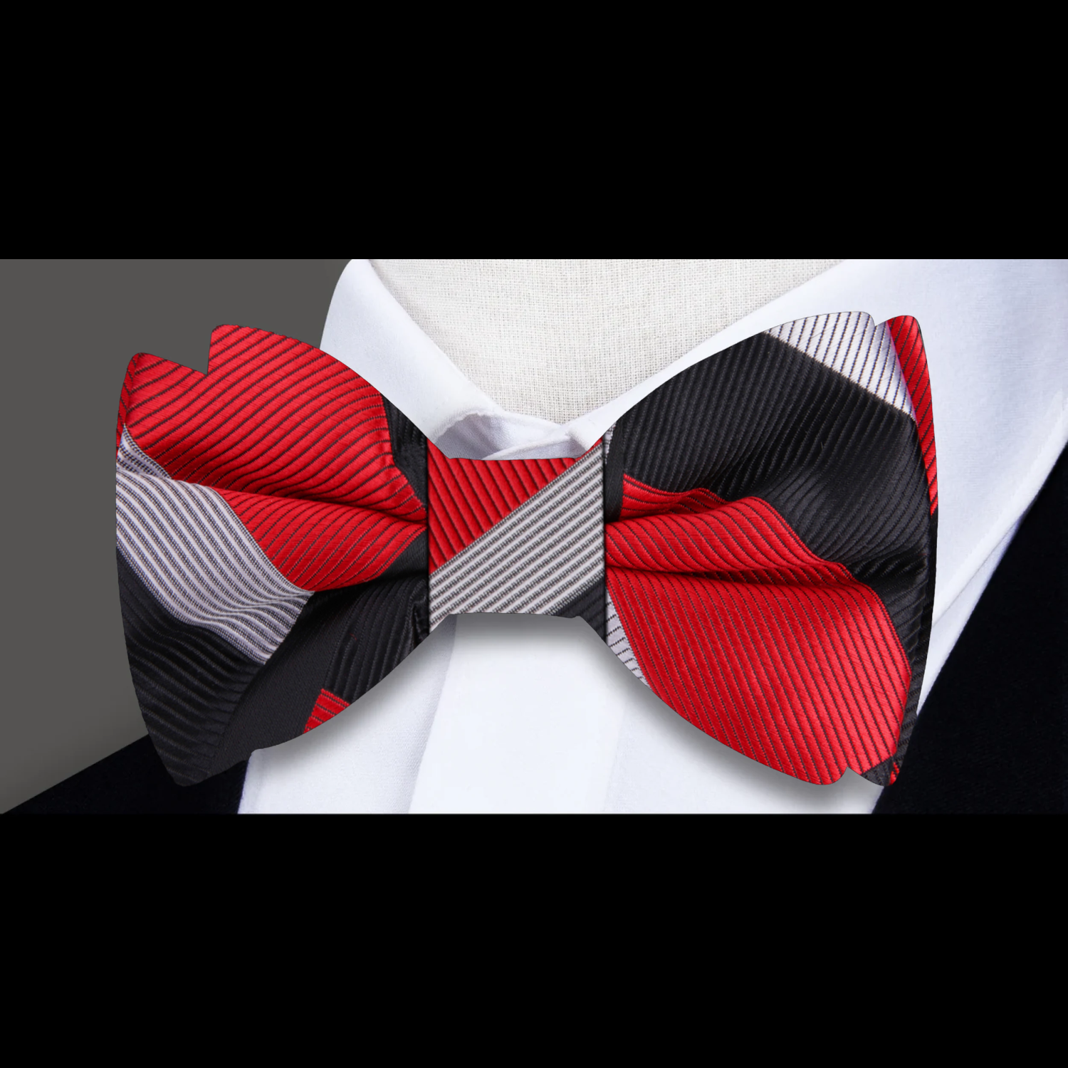 Styled on a pale grey micro-houndstooth shirt with a charcoal suit, showcasing the bow tie’s formal versatility