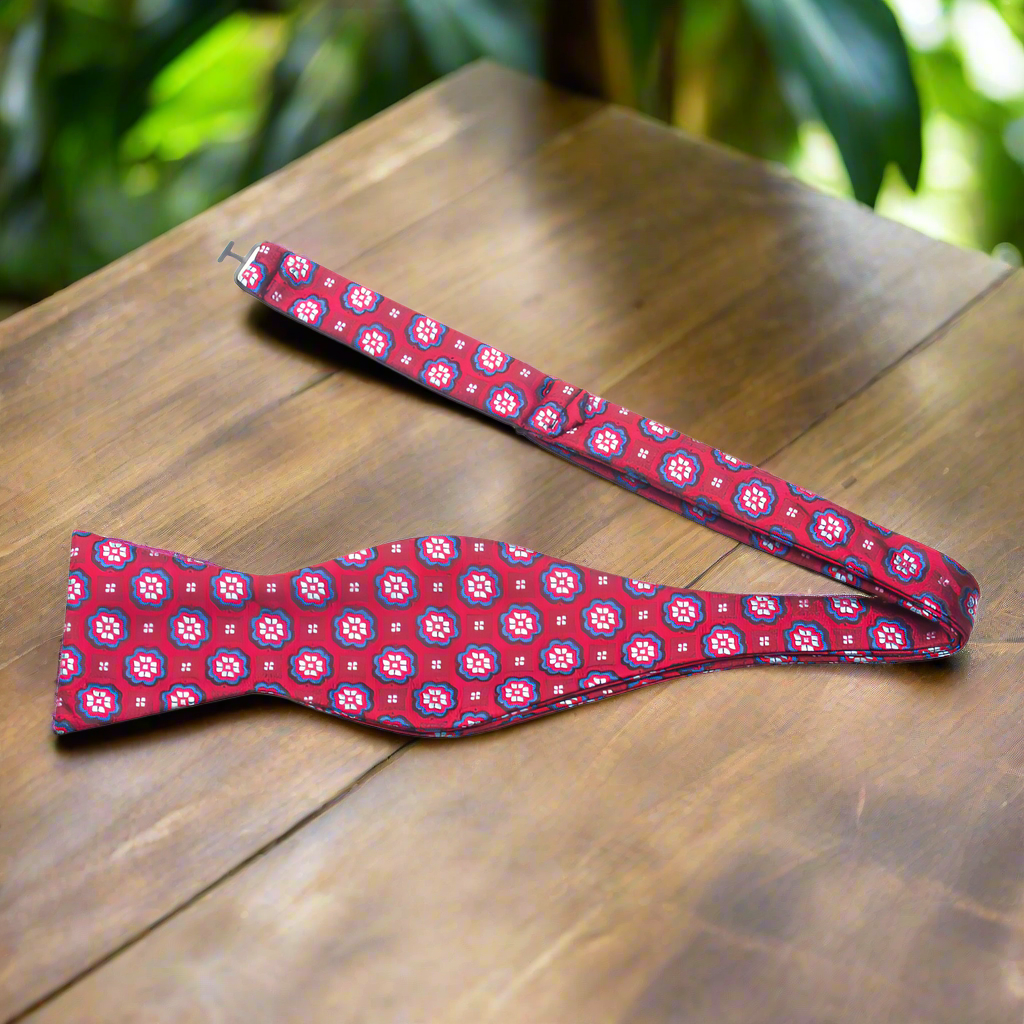 Close-up of the Crimson Burst Silk Bow Tie showcasing the intricate grey and red flower burst design.