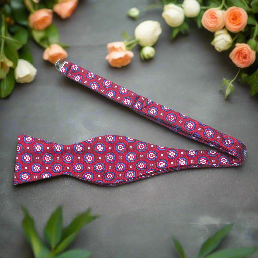 Man wearing a floral silk bow tie with a white shirt and navy suit for summer wedding