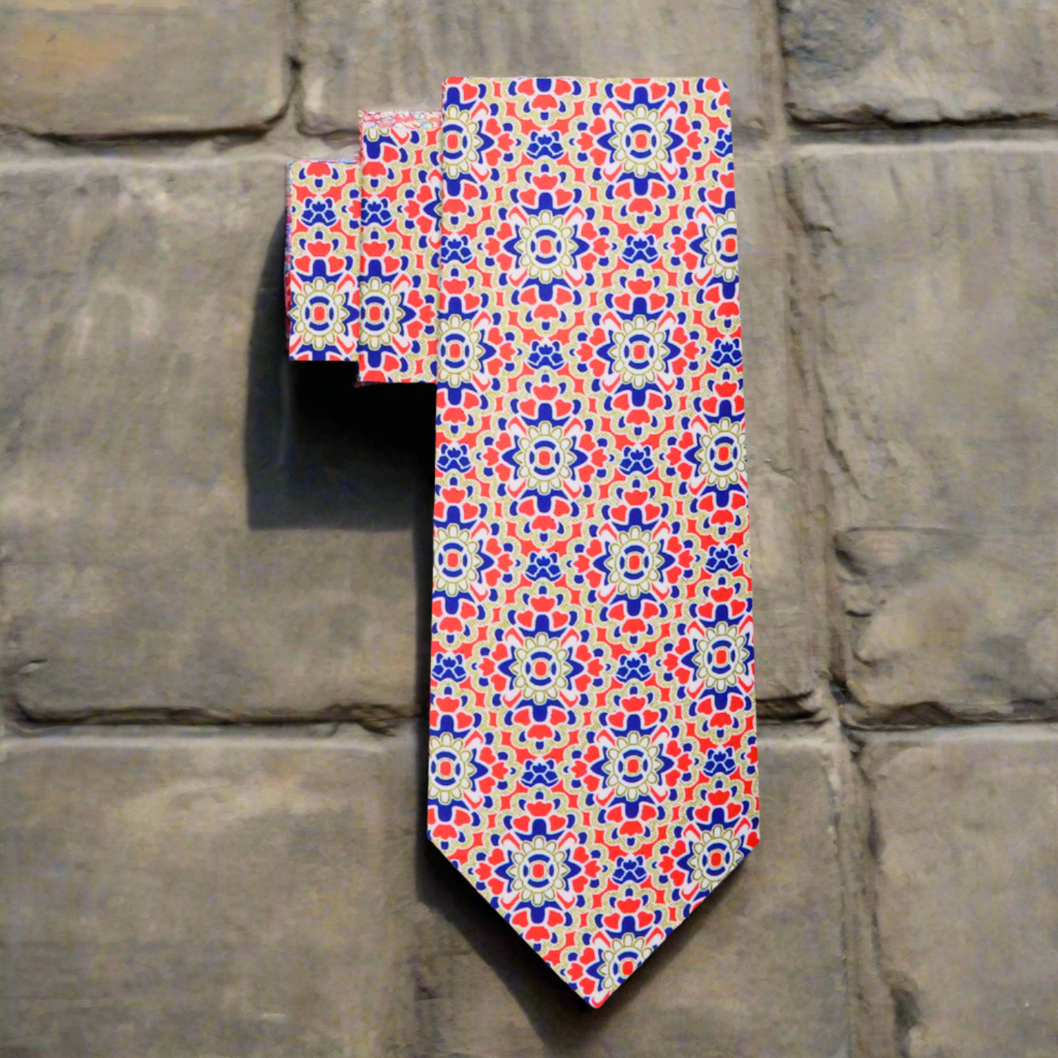 Flat lay of the vibrant geometric necktie and matching pocket square on a wooden table.