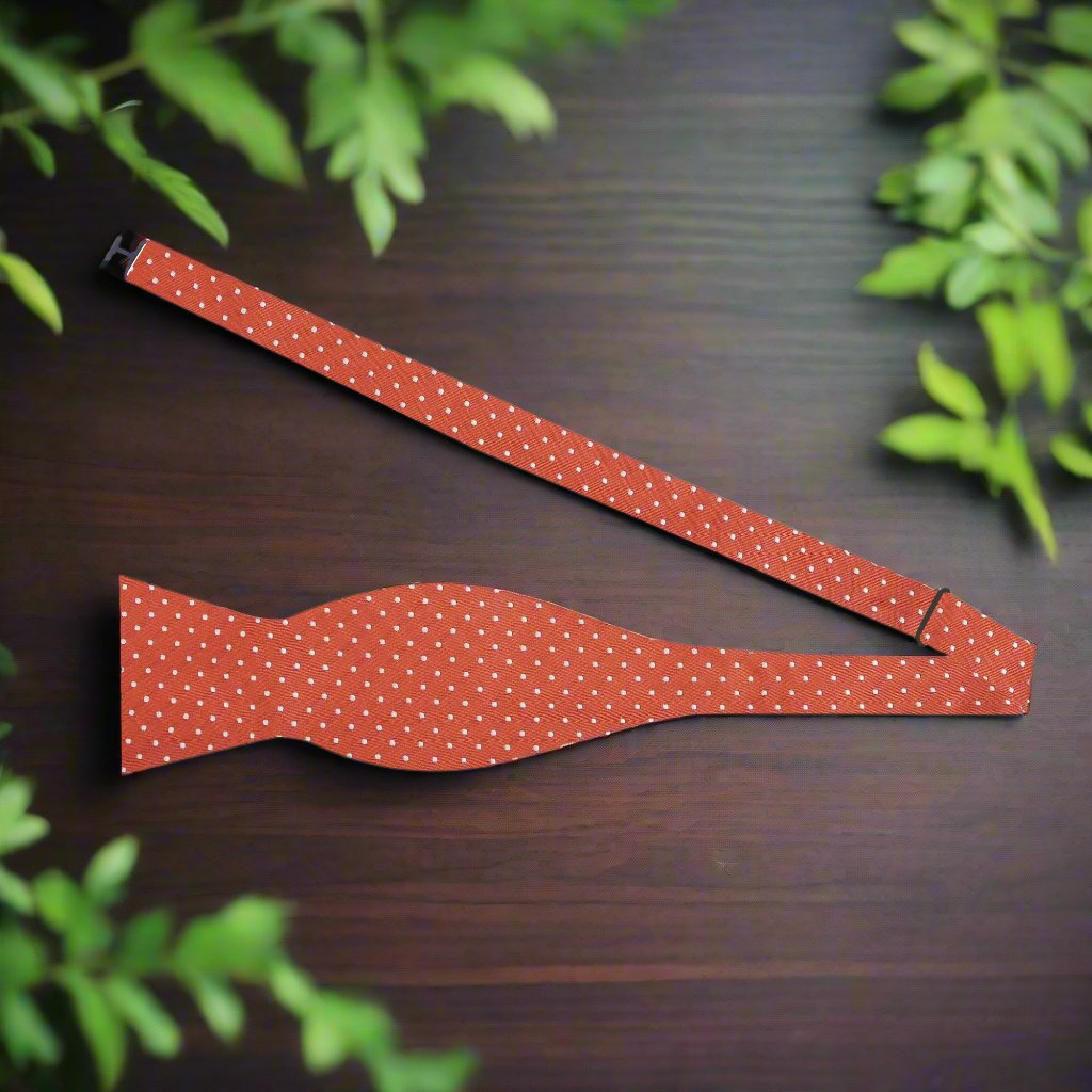 Vibrant orange polka dot bow tie displayed against a white background.