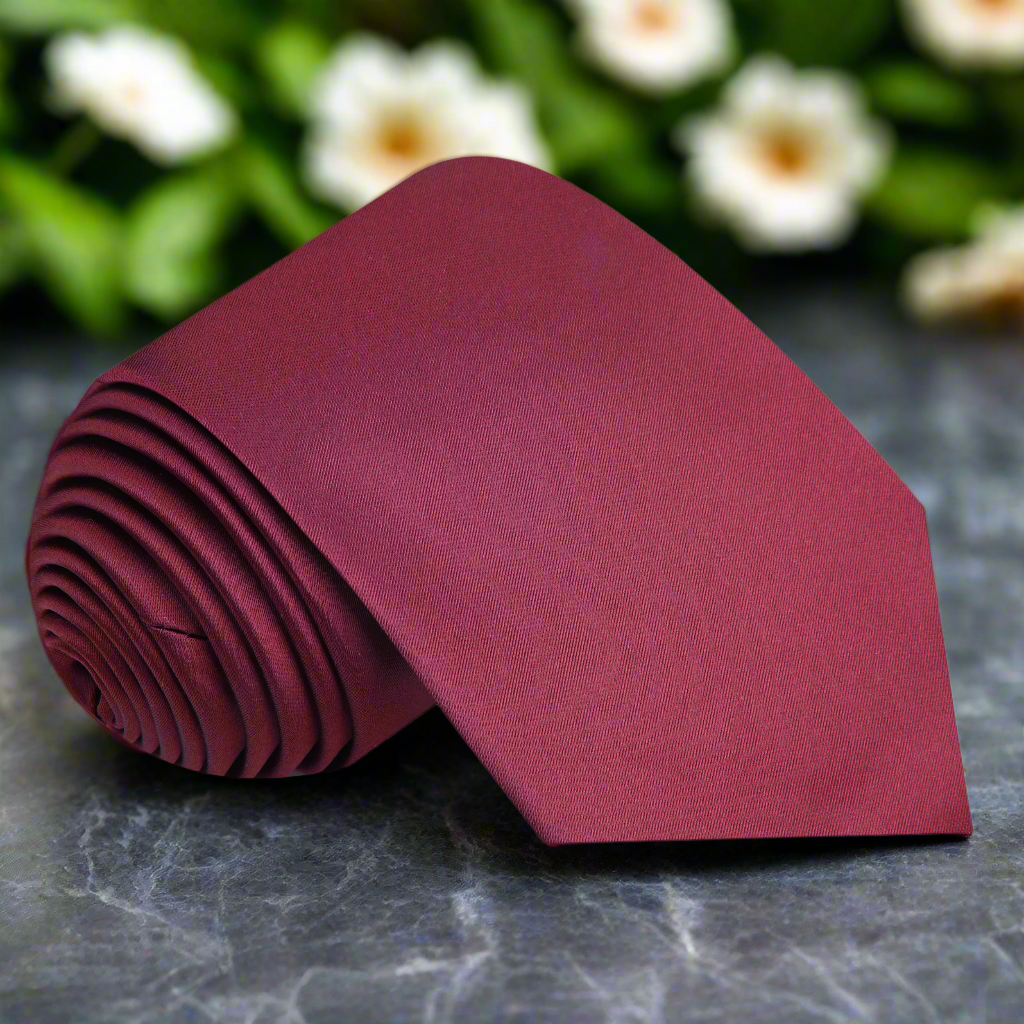Classic deep red silk necktie draped elegantly over a suit jacket, showcasing its rich color.