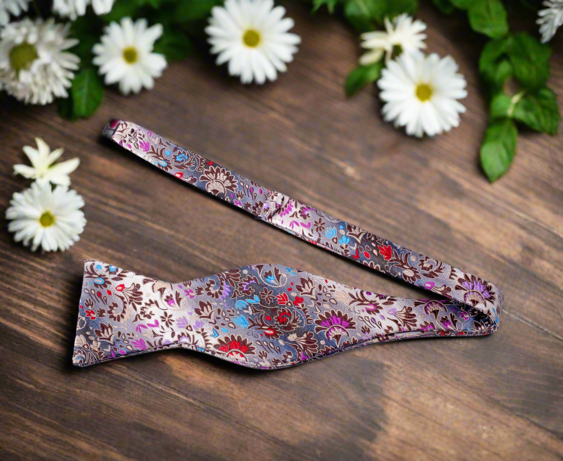 Close-up of a mens floral silk bow tie with brown and red flowers for fall weddings