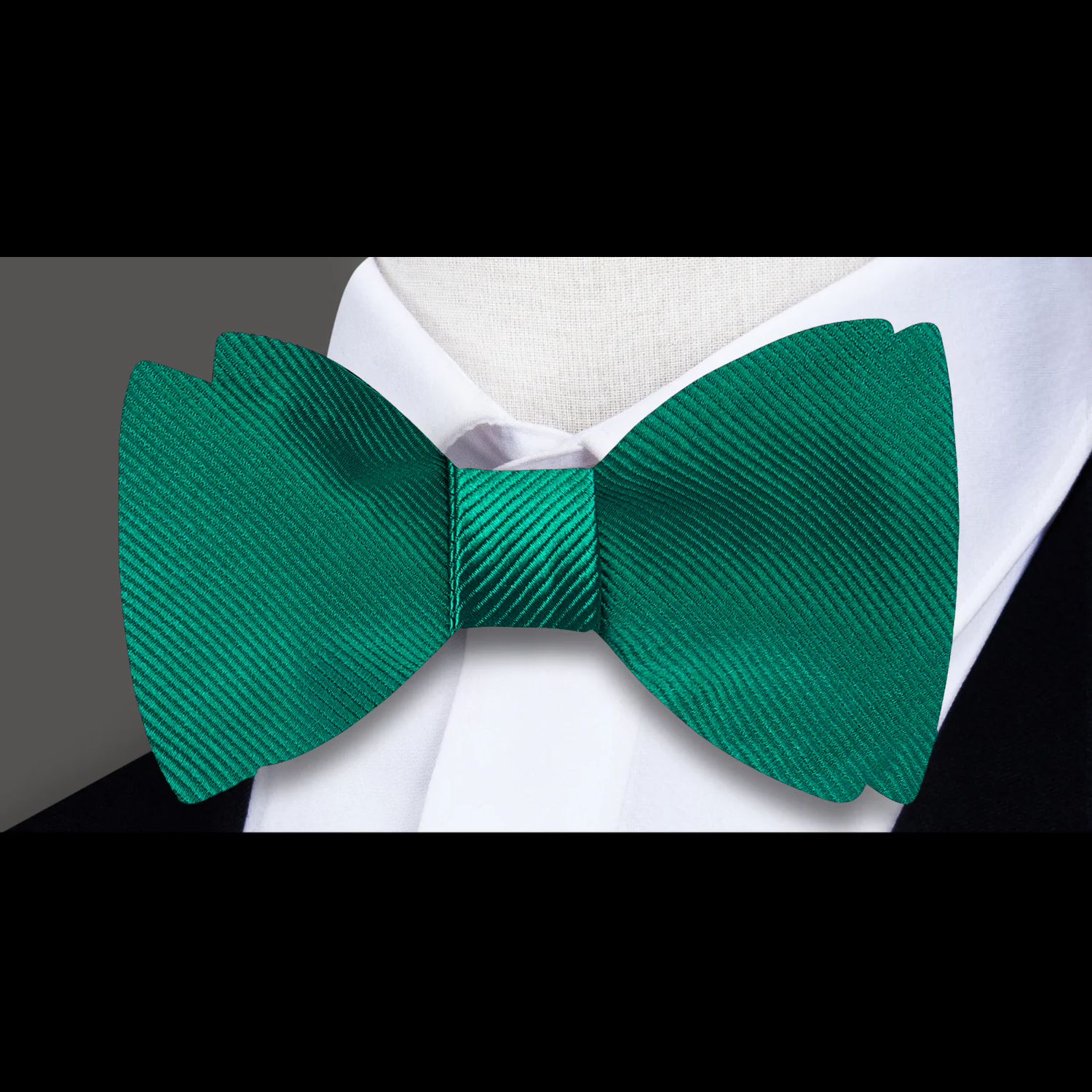 Close-up of the green silk bow tie showing its smooth texture and self-tie design