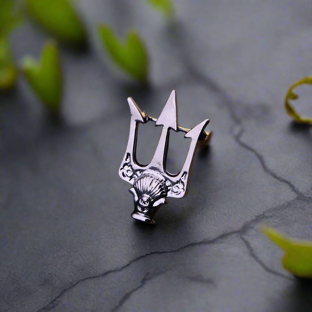 Close-up of the black and gold trident lapel pin with detailed design