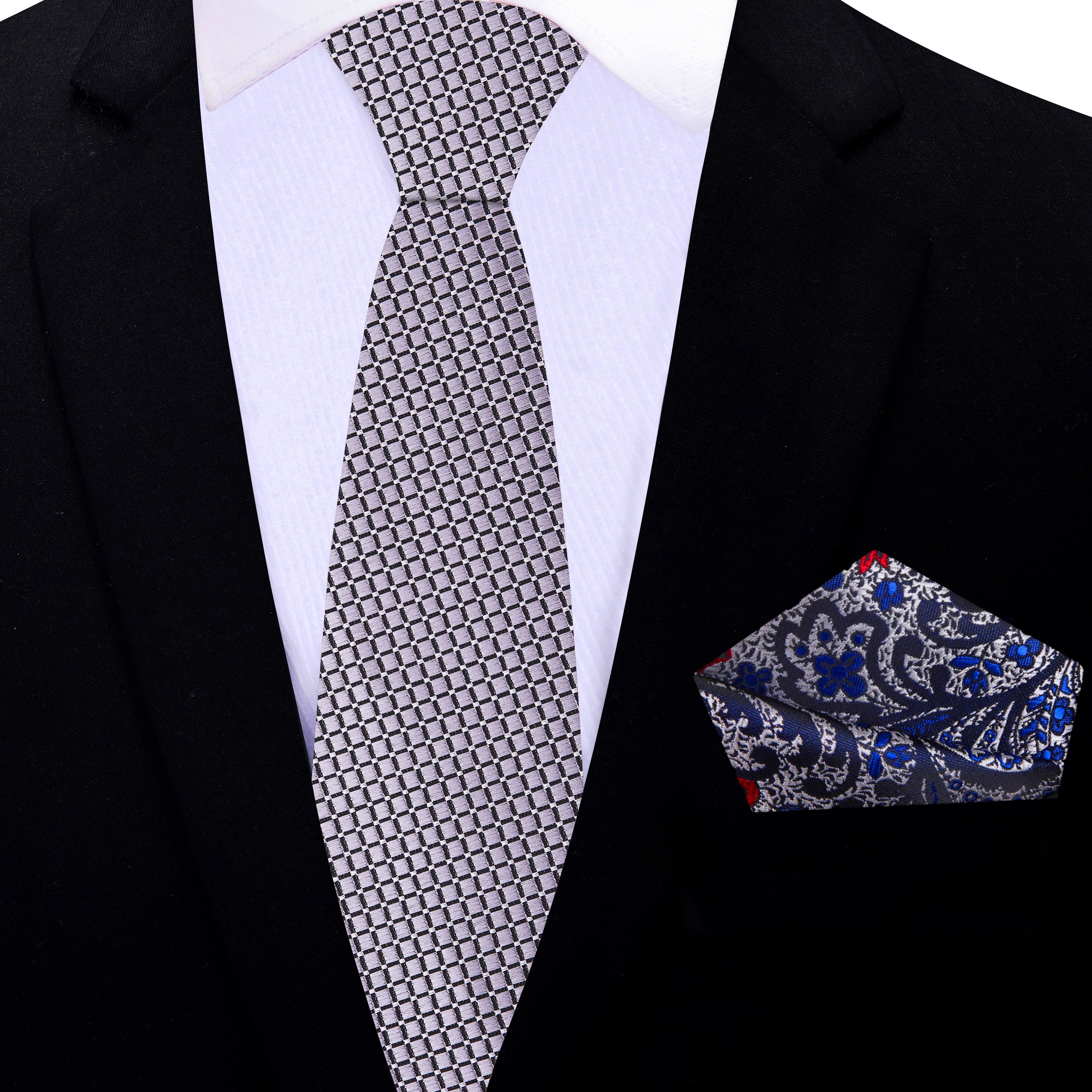 Elegant silver geometric necktie displayed with a charcoal suit background, emphasizing its modern design.