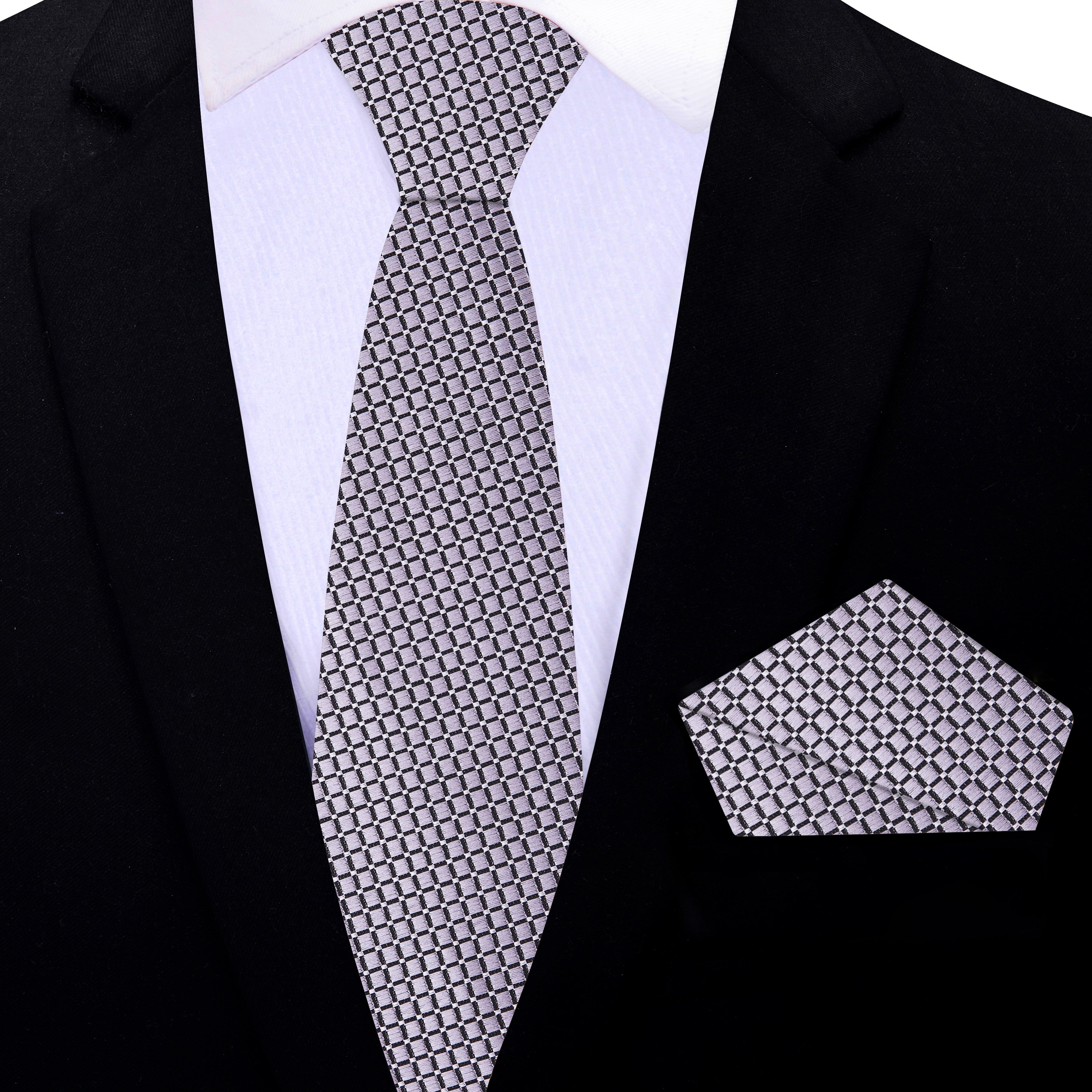 Elegant silver geometric necktie displayed with a charcoal suit background, emphasizing its modern design.