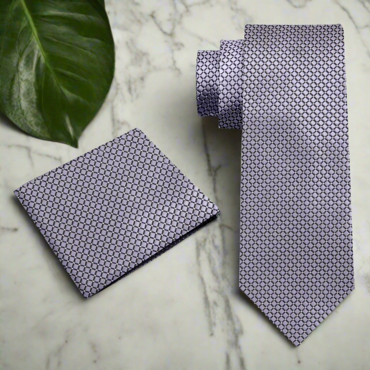 Silk tie with geometric pattern and metallic finish draped over a suit