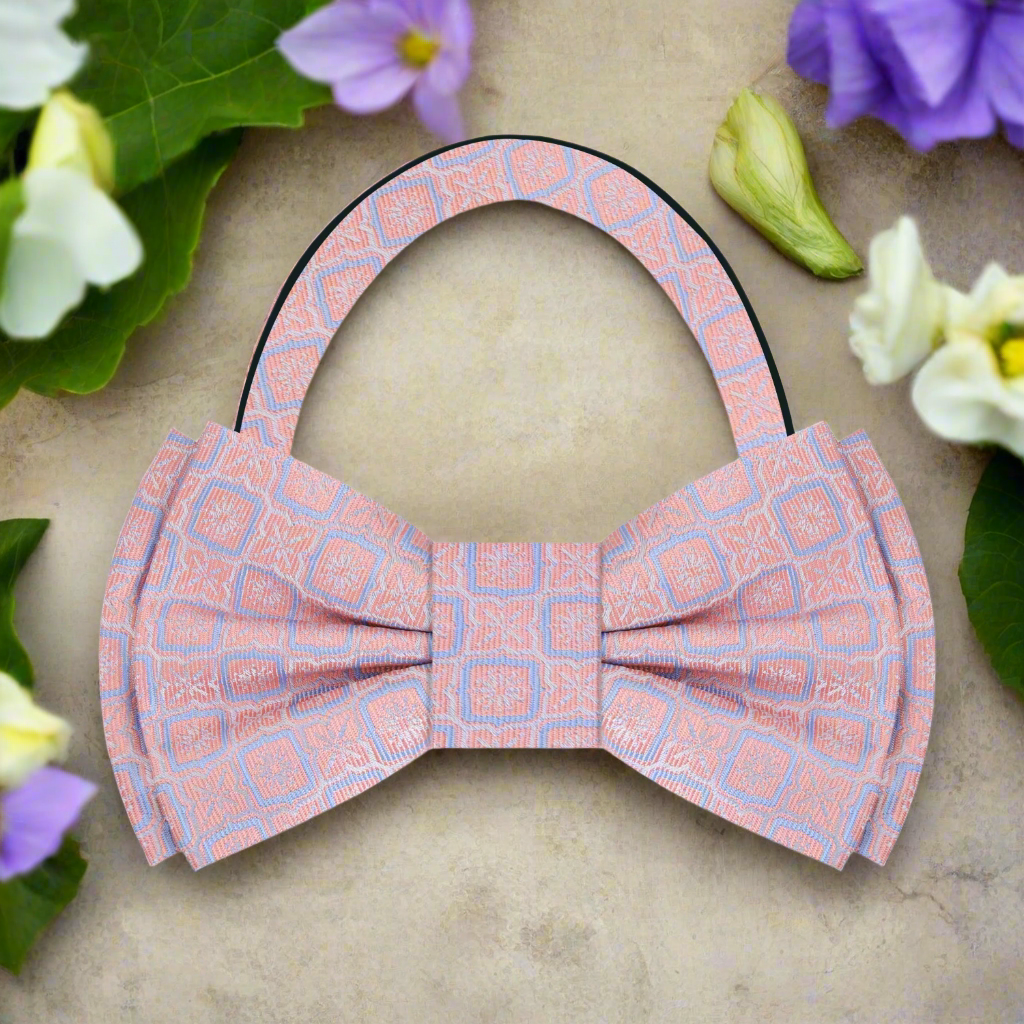 Flat lay of the vibrant geometric silk bow tie alongside a charcoal grey suit and a pocket square.