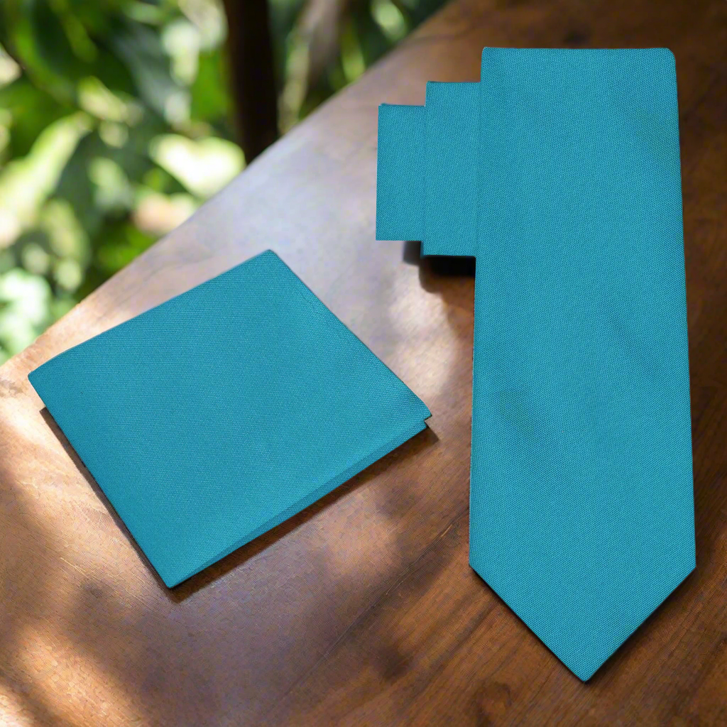 Caribbean Elegance Silk Tie displayed against a crisp white shirt, showcasing its vibrant blue-green color.