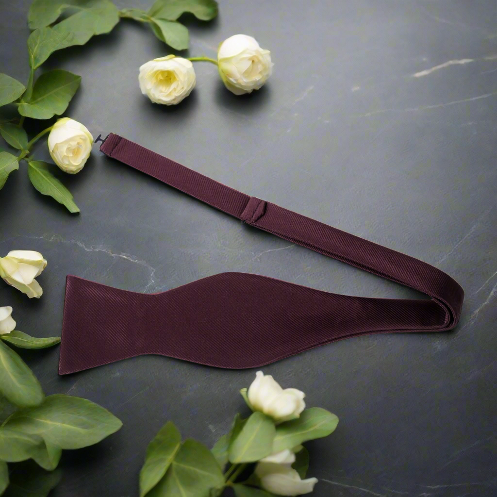 Elegant burgundy solid color bow tie paired with a crisp white shirt.