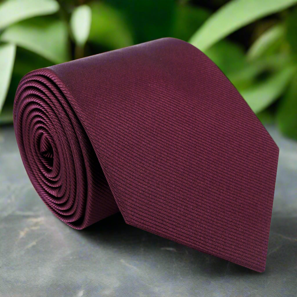 Elegant deep malbec silk necktie displayed on a wooden surface, emphasizing its rich color and luxurious texture.