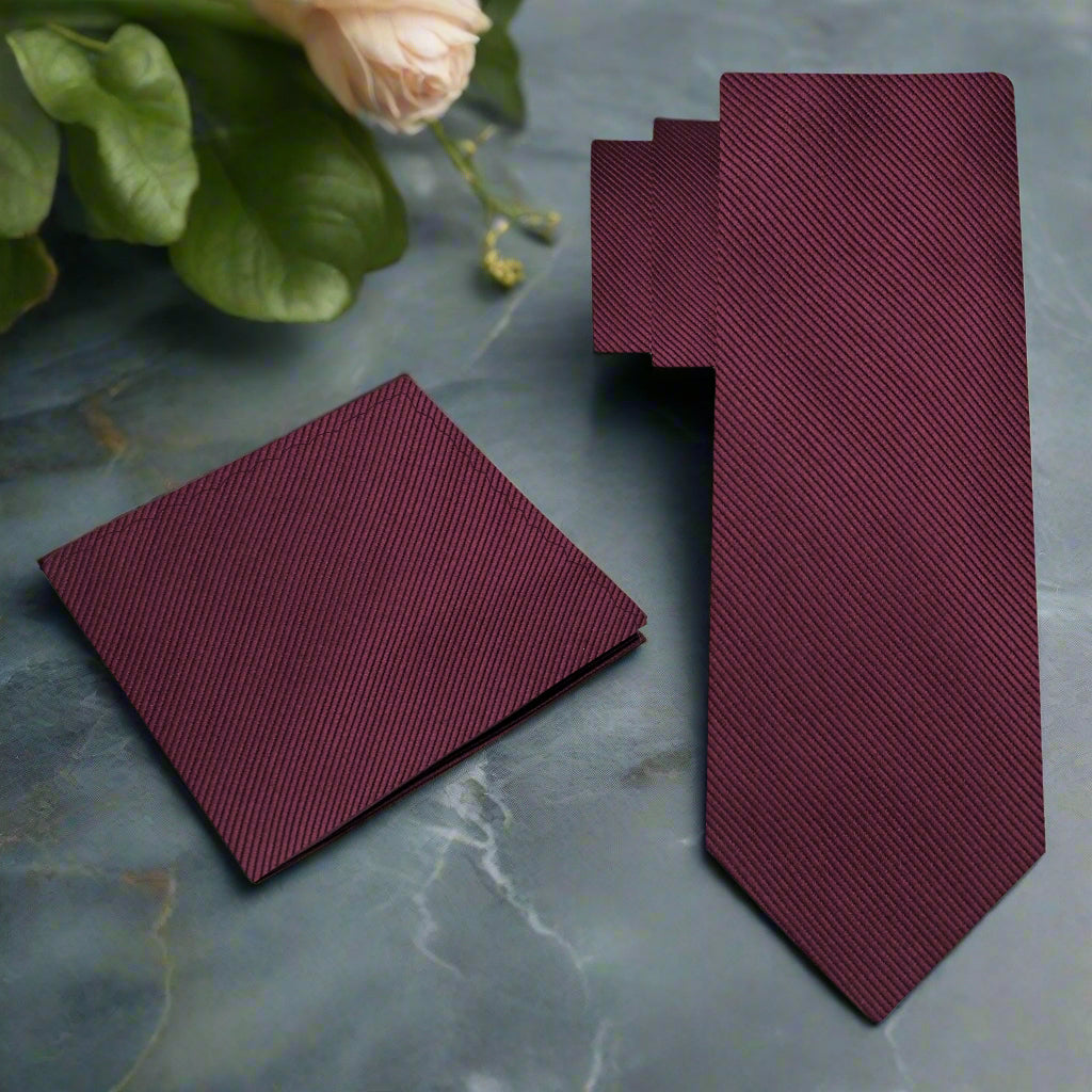 Elegant deep malbec silk necktie displayed on a wooden surface, emphasizing its rich color and luxurious texture.