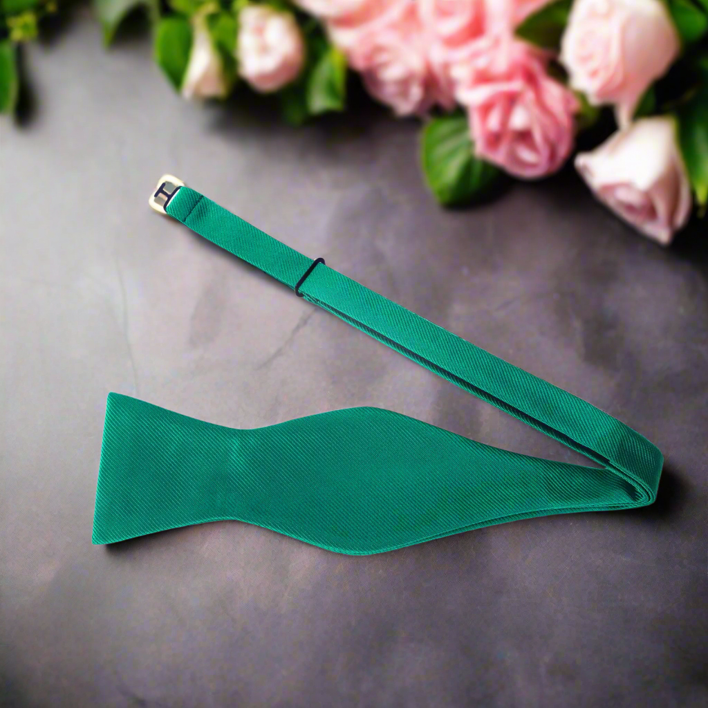 Bow tie and pocket square set displayed flat, highlighting the rich green color
