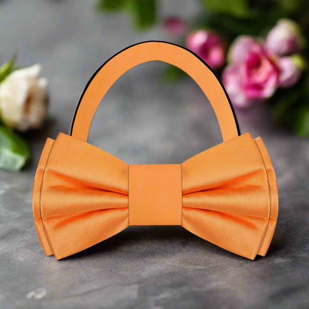 Close-up of the vibrant solid orange silk bow tie set against a crisp white dress shirt.