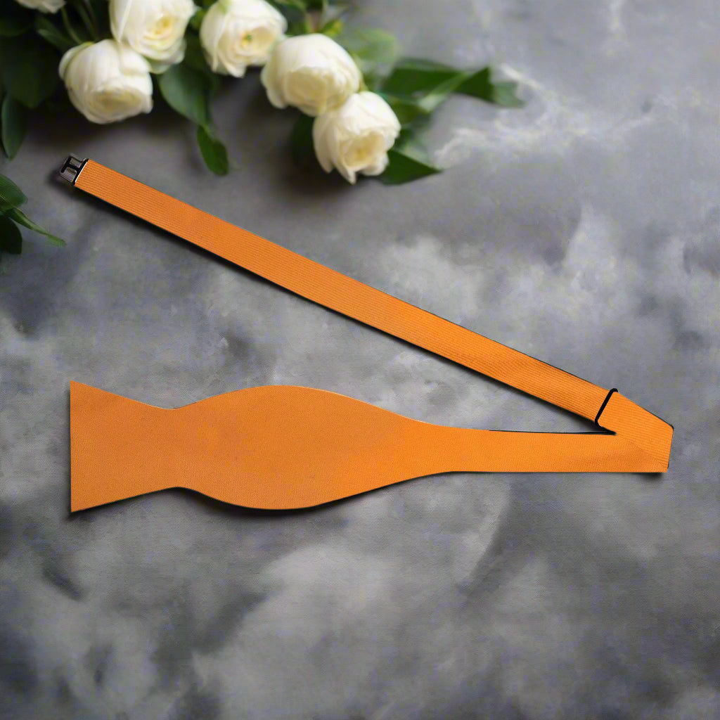 Orange bow tie paired with a navy suit, showcasing its elegant contrast for formal events.