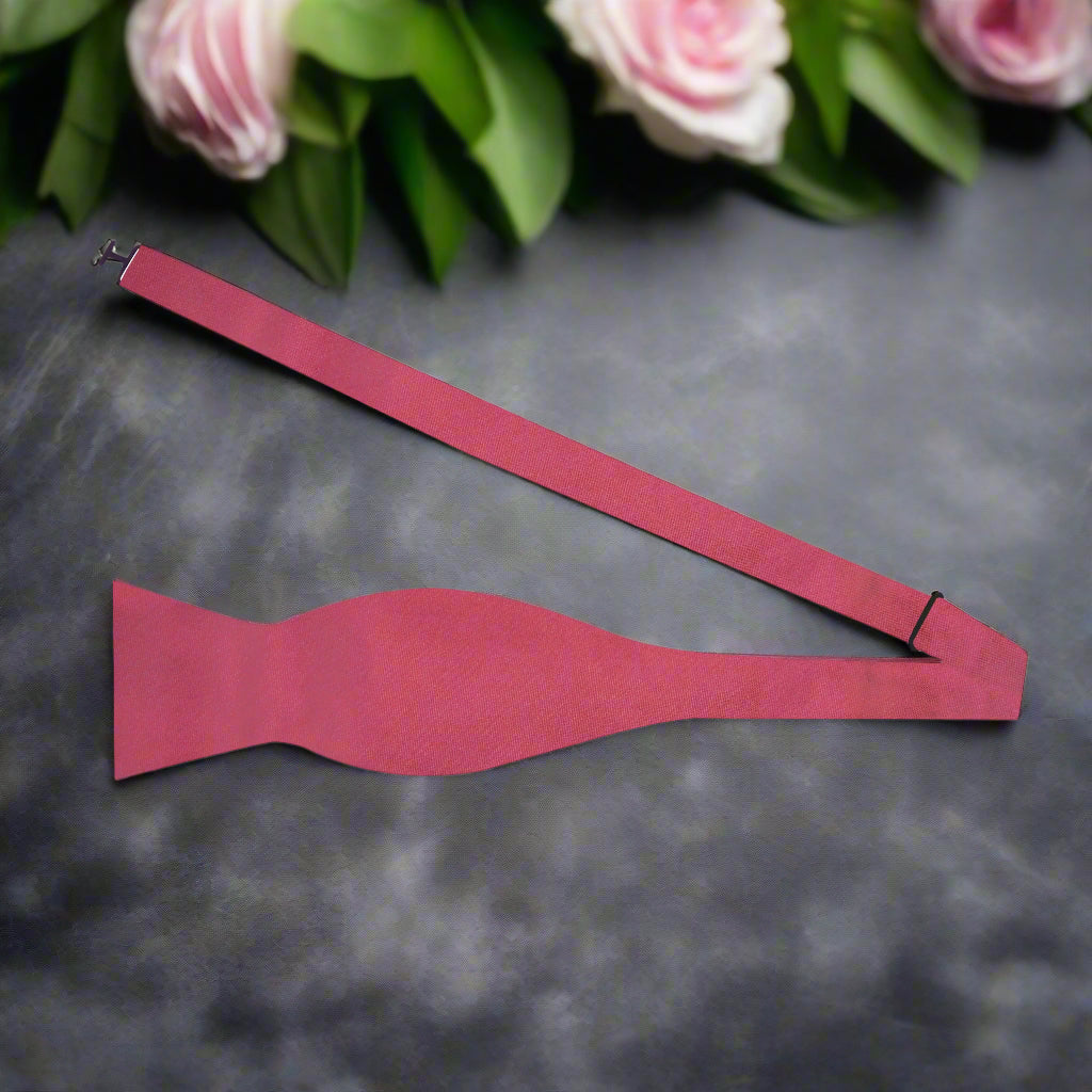 The deep red silk bow tie displayed alongside a navy suit, highlighting its sophisticated color contrast.