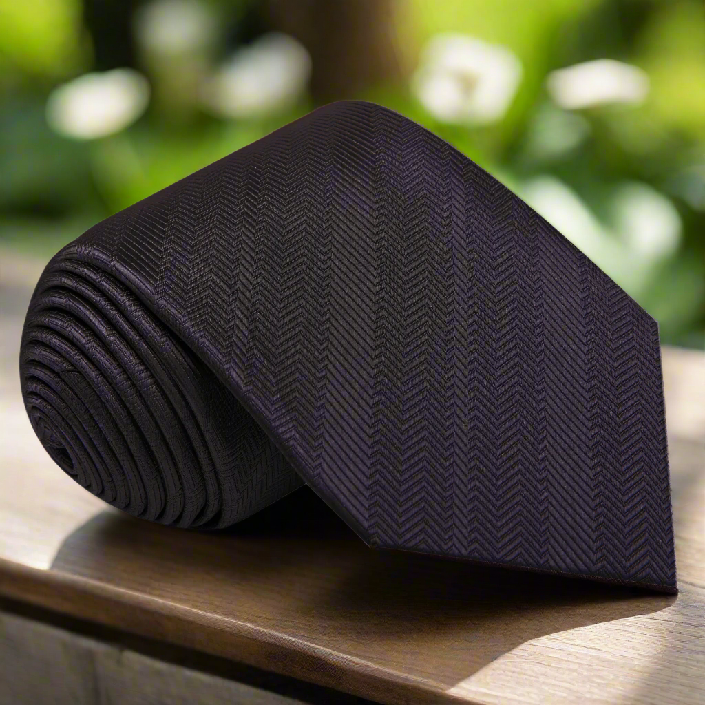 Elegant dark charcoal silk tie displayed on a white dress shirt, showcasing its texture.