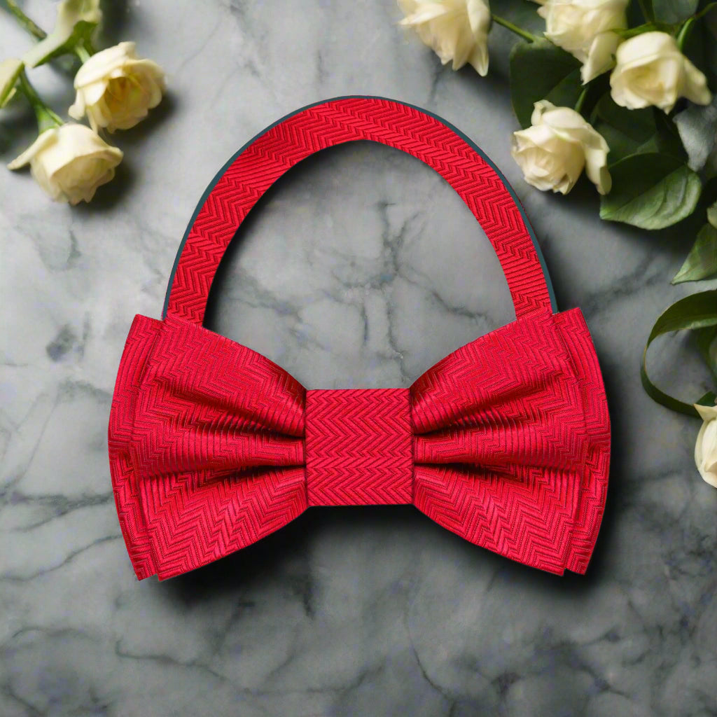Stylish garnet red silk bow tie paired with a matching pocket square on a navy blue suit jacket, ideal for weddings.