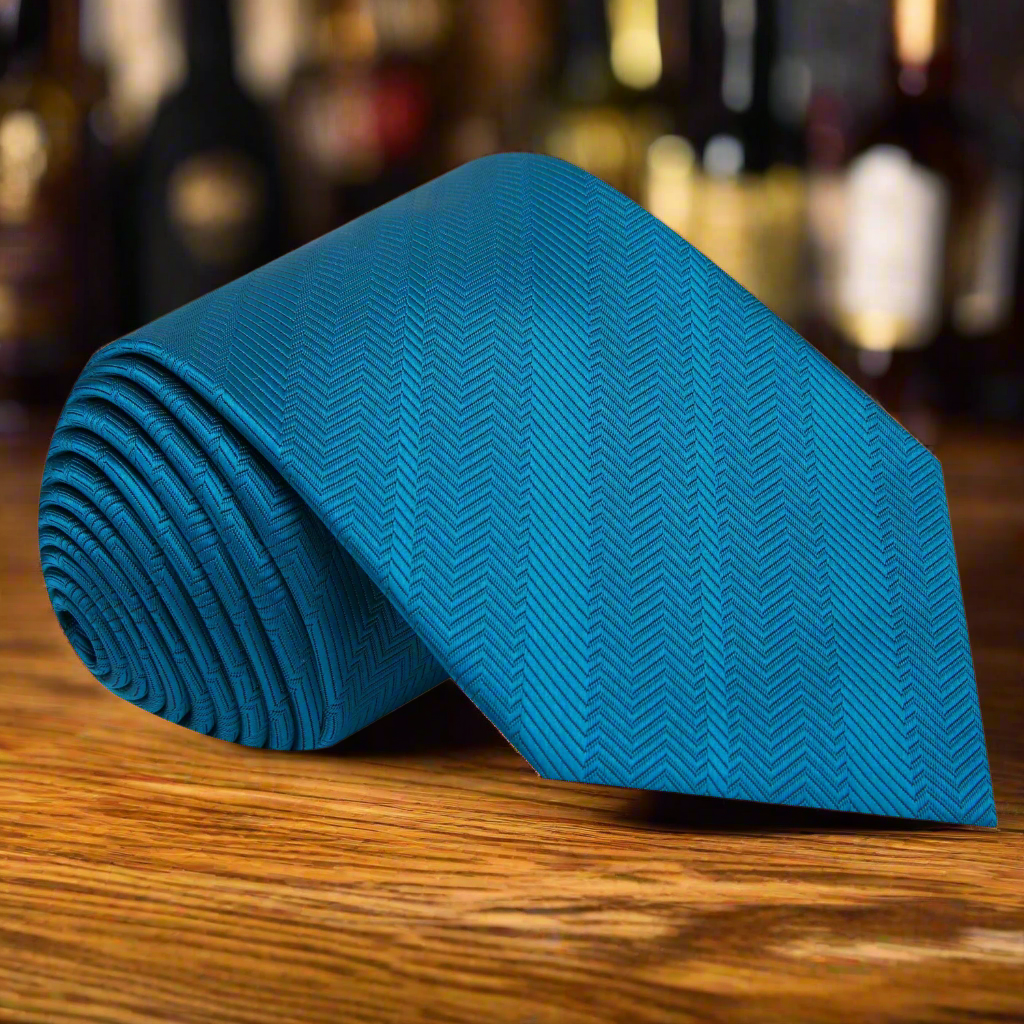 Elegant teal silk necktie displayed on a wooden table, showcasing its herringbone texture.