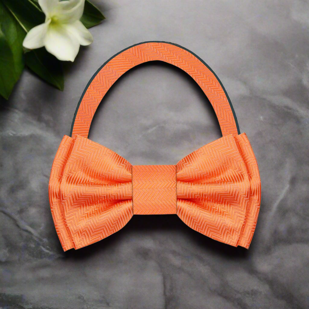 Orange silk bow tie paired with a charcoal grey suit, ideal for business events.