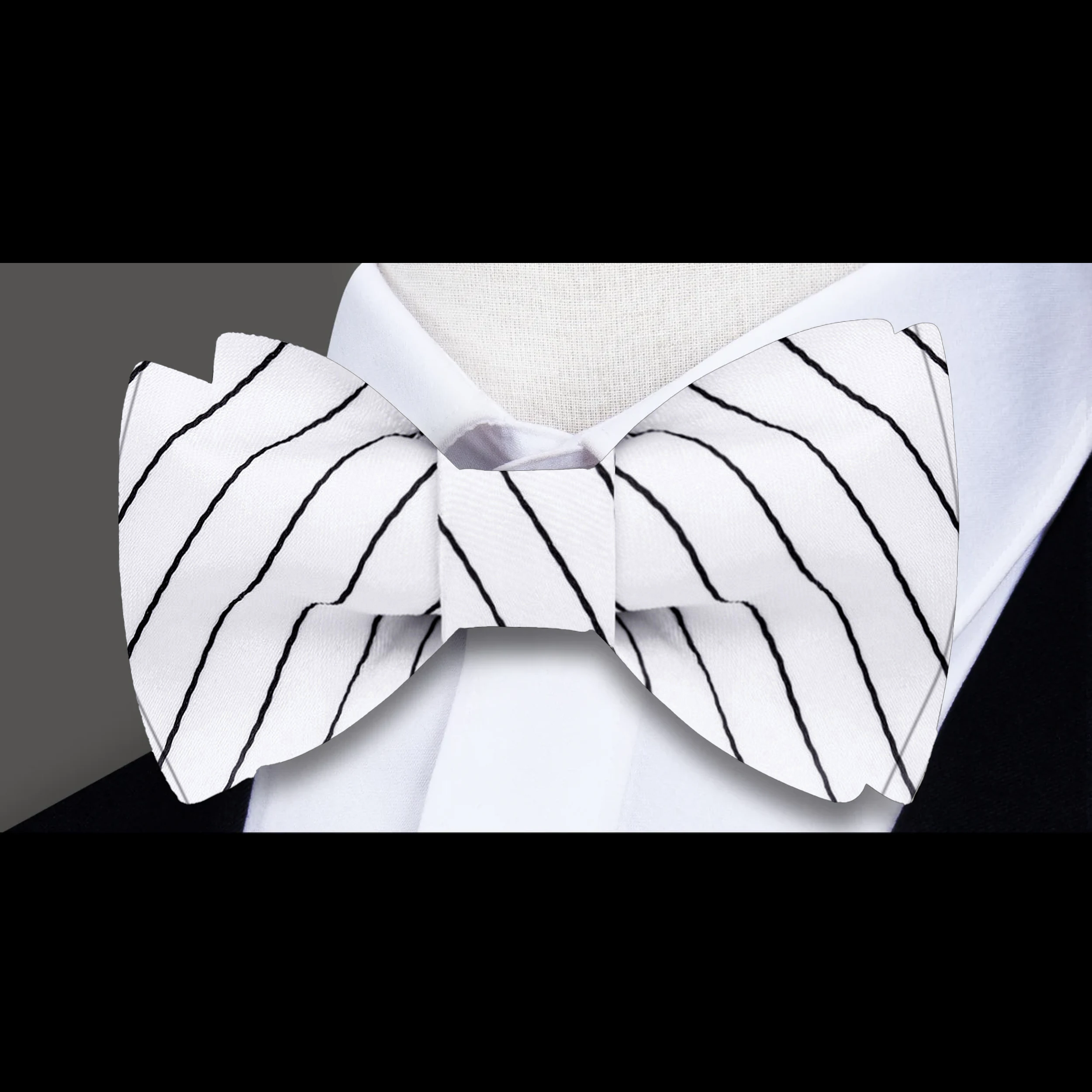 Flat lay of white and black striped bow ties with matching pocket squares, ideal for formal occasions.